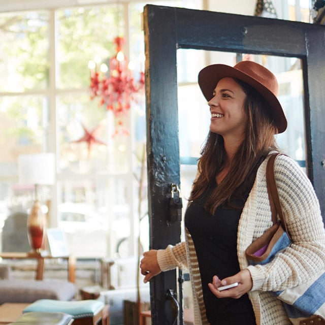 Woman entering store with smartphone in hand.