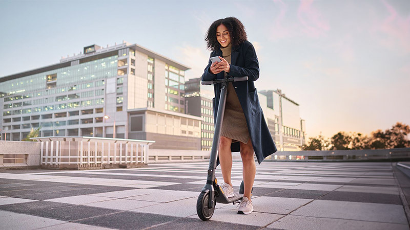 Woman with skateboard using her cell phone in the city